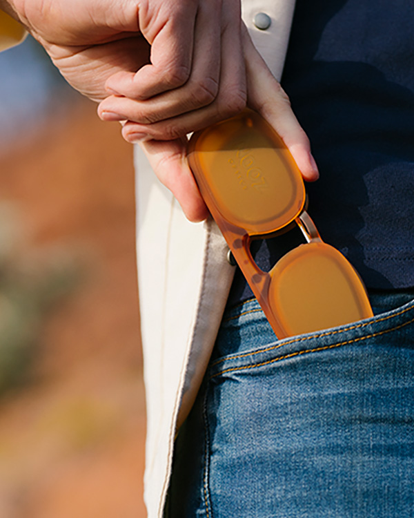 a person holding a pair of orange sunglasses.